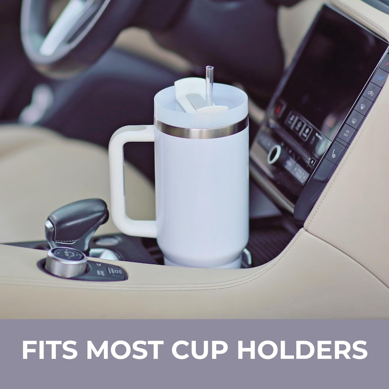 May include: A white insulated tumbler with a sturdy handle, a clear lid, and a transparent straw. The cylindrical container features a metallic rim and is positioned in a vehicle cup holder. The text FITS MOST CUP HOLDERS is displayed below.