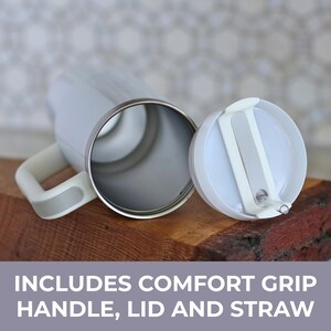 May include: A white tumbler with a metallic rim, featuring a side handle with a comfort grip, a matching white lid, and a clear straw. The text on the image reads: INCLUDES COMFORT GRIP HANDLE, LID AND STRAW. The tumbler is shown from an overhead angle.