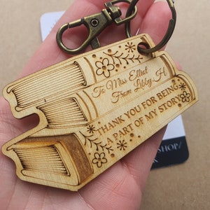 Może przedstawiać: Drewniany brelok do kluczy w kształcie książki z napisem "To Miss Elliat From Libby H THANK YOU FOR BEING A PART OF MY STORY".