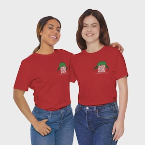May include: Two people wearing matching red t-shirts with a green graphic of a hat and a QR code. The text "You Should Care!" is below the graphic. They are wearing blue jeans.