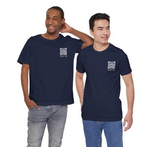 May include: Two navy blue t-shirts with a white QR code and the text "Scan me" printed on the upper left chest. The shirts are worn by two people, paired with blue jeans.