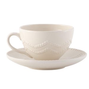 May include: Cream-colored teacup and saucer set. The cup features a curved handle and a decorative wave pattern. The saucer has a matching design around the rim. The set is made of ceramic.