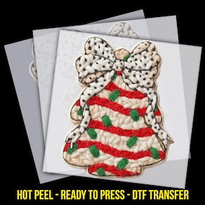 May include: A DTF transfer featuring a bell-shaped design with a bow. The bell has a red and white striped pattern with green accents. The bow is white with black polka dots. The text "HOT PEEL - READY TO PRESS - DTF TRANSFER" is at the bottom.