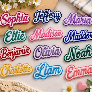 May include: A collection of twelve custom name plaques in various colors, each featuring a raised script font with a white outline. The names displayed are Sophia, Jeffery, Maria, Ellie, Madison, Maddox, Benjamin, Olivia, Noah, Charlotte, Liam, and Emma.
