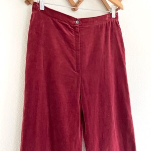 Puede incluir: Un pantal&oacute;n de pierna ancha de color burdeos oscuro. El pantal&oacute;n est&aacute; hecho de una tela suave y aterciopelada y tiene una cintura alta.