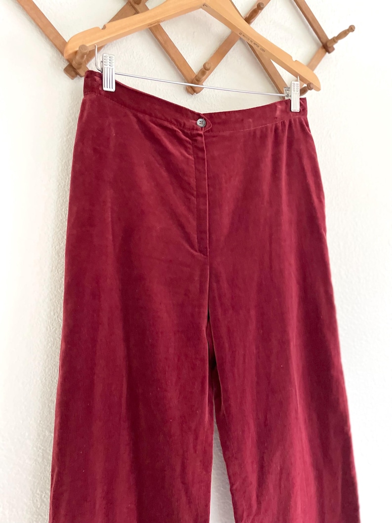 Puede incluir: Un pantal&oacute;n de pierna ancha de color burdeos oscuro. El pantal&oacute;n est&aacute; hecho de una tela suave y aterciopelada y tiene una cintura alta.