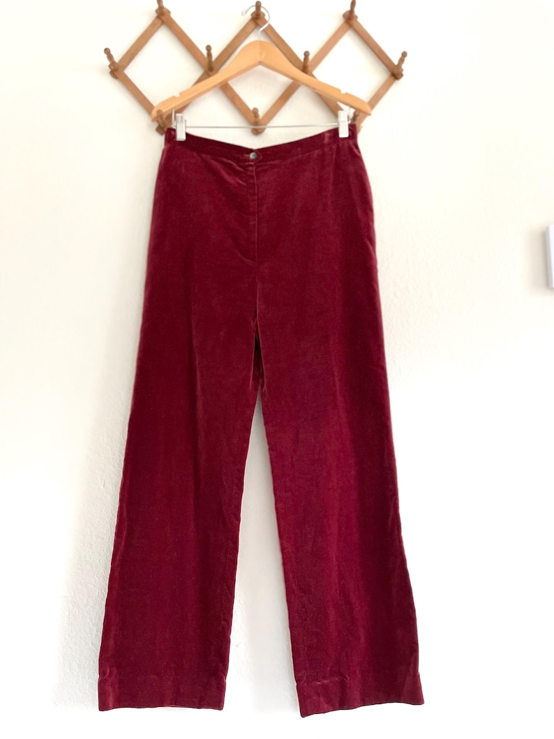 Puede incluir: Un pantal&oacute;n de pierna ancha en color burdeos oscuro. El pantal&oacute;n est&aacute; hecho de una tela suave y aterciopelada y tiene una cintura alta.