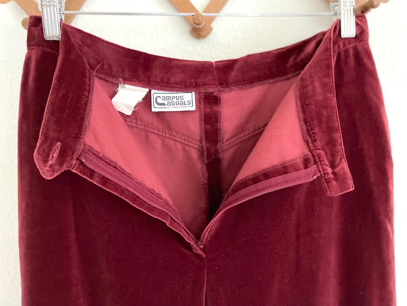 Puede incluir: Un pantal&oacute;n de terciopelo burdeos con cierre de cremallera y una etiqueta que dice "Campus Casuals of California".