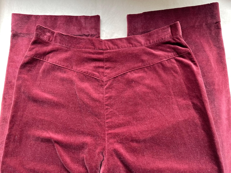 Puede incluir: Un pantal&oacute;n de terciopelo burdeos de cintura alta y pierna recta.