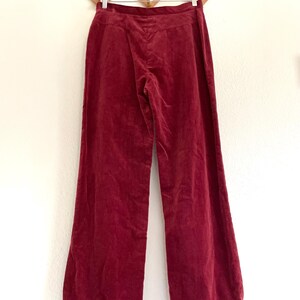 Puede incluir: Un par de pantalones de pierna ancha en color burdeos oscuro. Los pantalones est&aacute;n hechos de una tela suave y aterciopelada y tienen una cintura alta.
