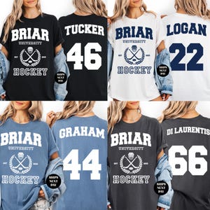May include: A collection of hockey-themed t-shirts in various colors, including black, white, blue, and gray. Each shirt features the word "BRIAR UNIVERSITY HOCKEY" with a hockey stick and puck graphic. Some shirts display names and numbers.