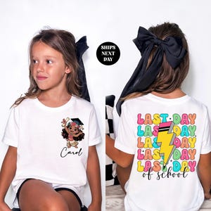 A young girl wearing a white t-shirt with a cartoon character and text printed on it.