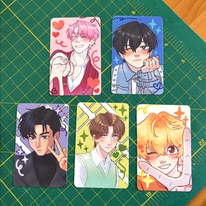 May include: Five rectangular trading cards featuring anime-style illustrations of individuals. The cards display characters with pink, black, brown, and blonde hair, decorated with colorful hearts, stars, and swirling graphic elements.
