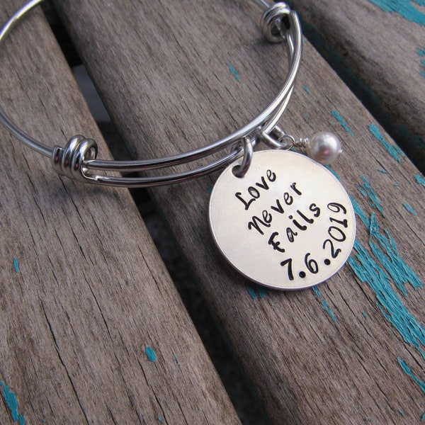 Love Never Fails Bracelet- Hand-Stamped "Love Never Fails (date)" Bracelet with an accent bead in your choice of colors