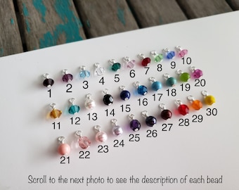 May include: A white card with 30 different colored beads arranged in rows. Each bead is numbered from 1 to 30. The card has the text "Scroll to the next photo to see the description of each bead".