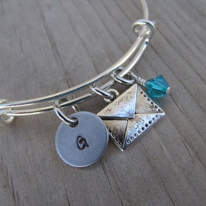 May include: Silver charm bracelet with a letter 'A' charm, a silver envelope charm, and a teal blue crystal charm.