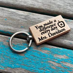 May include: Wooden keychain with a silver ring and the text "You made a difference every day Mrs. Davidson" with a small apple graphic.