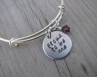 May include: Silver expandable bracelet with a charm that reads "proud to be me" and a small purple crystal charm.