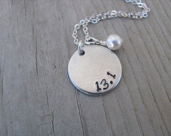 May include: Silver necklace with a round pendant that says "13.1" and a small pearl charm.