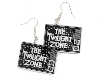May include: Silver-tone earrings with a black and white television design. The earrings feature the text "THE TWILIGHT ZONE" in white, with a retro style. The earrings are suspended from a simple hook.