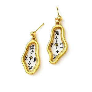 May include: A pair of gold-colored earrings in a surrealist design. Each earring features a melting clock face with Roman numerals and black hands against a white background. The earrings have a post and ball closure.