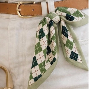 May include: A white ceramic mug with a black handle and the text "But First, Coffee" in a black, handwritten-style font. The mug is on a white surface.