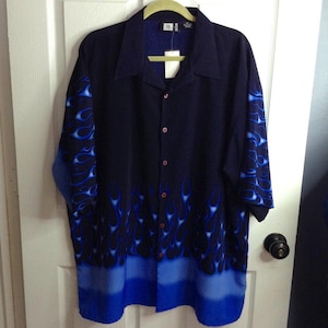 May include: Black button-down shirt with blue flame design. The shirt has a collar and long sleeves. The flames are a bright blue color and are placed on the sleeves and the bottom of the shirt.