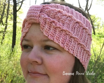 May include: A pink crocheted headband with a knotted design. The headband is worn by a person with brown hair. The text "Banana Moon Studio" is visible in the lower right corner of the image.