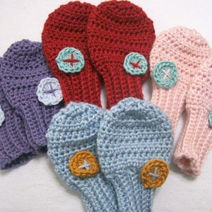May include: Six pairs of crocheted fingerless gloves with colourful buttons. The gloves are in shades of purple, blue, pink and red.