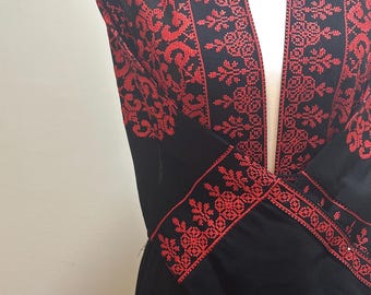 May include: Black jacket with intricate red embroidery. The embroidery features floral and geometric patterns along the edges, sleeves, and front panels. The jacket is displayed on a white mannequin.