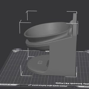 Puede incluir: Un cuenco gris para mascotas, impreso en 3D, con una base redondeada y un cuenco circular elevado. El cuenco está sostenido por una estructura vertical con un diseño curvo. El cuenco está sobre una superficie negra con un patrón de cuadrícula.