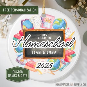 May include: A white ceramic ornament with a school theme. The ornament features a chalkboard with the words "First Year in Homeschool" and the names "Liam & Emma" with the year "2025". The design includes globes, books, and apples.