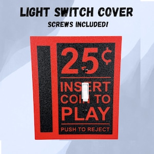 May include: A rectangular light switch cover featuring a red and black design with the text 25¢ INSERT COIN TO PLAY PUSH TO REJECT. The cover includes a central white toggle switch and two black mounting screws for installation on a wall plate.