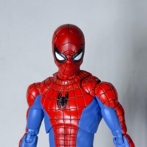 Puede incluir: Figura de acci&oacute;n detallada de Spider-Man, con un traje rojo y azul y un emblema de ara&ntilde;a negra en el pecho. La figura tiene una m&aacute;scara roja con lentes blancos. Fondo liso.