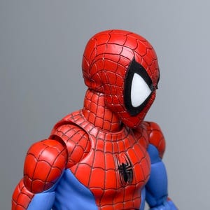 Puede incluir: Figura de acci&oacute;n detallada de Spider-Man, con un traje rojo y azul y un emblema de ara&ntilde;a en el pecho. La figura tiene una m&aacute;scara roja con lentes oculares blancas y contornos negros. El traje est&aacute; intrincadamente dise&ntilde;ado con patrones de telara&ntilde;a.