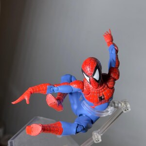 Puede incluir: Figura de acci&oacute;n de Spider-Man en rojo y azul, en una pose din&aacute;mica en el aire. La figura tiene un disfraz detallado con patrones de telara&ntilde;a y un emblema de ara&ntilde;a negra. Se apoya en un soporte de pl&aacute;stico transparente.