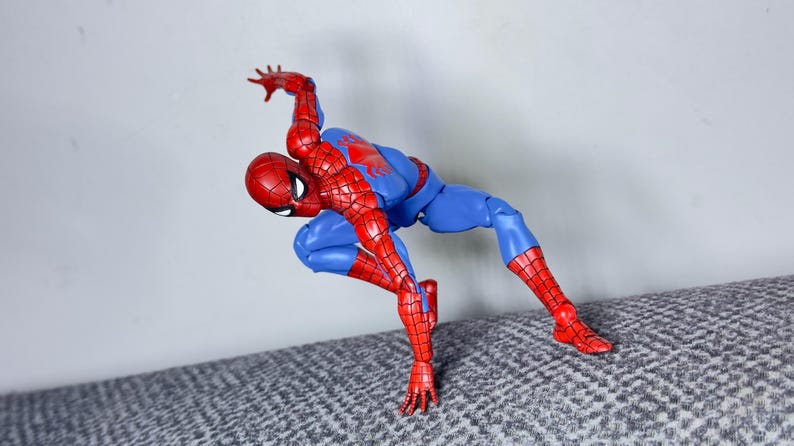 Puede incluir: Figura de acci&oacute;n de Spider-Man en pose din&aacute;mica, con traje rojo y azul. La figura est&aacute; doblada por las rodillas y la cintura, con un brazo extendido hacia arriba. Mide unos 15 cm de alto.