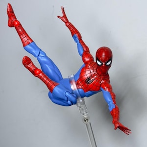 Puede incluir: Figura de acci&oacute;n de Spider-Man en una pose din&aacute;mica, con un traje rojo y azul. La figura est&aacute; suspendida en el aire, mostrando sus extremidades articuladas y su ic&oacute;nico dise&ntilde;o de telara&ntilde;a. La figura mide aproximadamente 15 cm de altura.