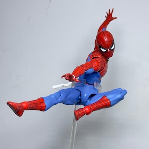Puede incluir: Figura de acci&oacute;n de Spider-Man, rojo y azul, en una pose din&aacute;mica, suspendida en el aire. La figura presenta una m&aacute;scara, torso y extremidades rojas, con detalles azules. Montada sobre un soporte transparente, muestra el ic&oacute;nico disfraz.