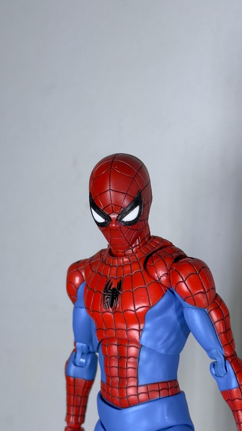 Puede incluir: Figura de acci&oacute;n de Spider-Man rojo y azul. La figura tiene una m&aacute;scara roja con ojos blancos y un emblema de ara&ntilde;a negra en el pecho. La figura lleva un traje rojo y azul con un patr&oacute;n de telara&ntilde;a.