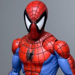 Puede incluir: Figura de acci&oacute;n detallada de Spider-Man, con su traje rojo y azul con un dise&ntilde;o de telara&ntilde;a. La figura tiene un emblema de ara&ntilde;a negra en el pecho y lentes oculares blancas. Fondo gris.