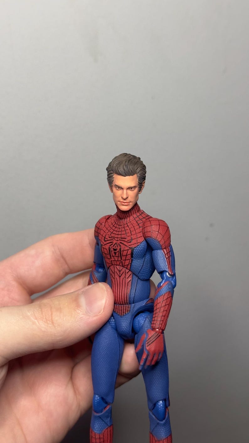 Może przedstawiać: Szczeg&oacute;łowa figurka Spider-Mana w klasycznym kostiumie. Figurka ma czerwono-niebieski kostium z detalami pajęczyny, czerwony emblemat pająka na klatce piersiowej i realistyczną rzeźbę głowy. Figurka ma około 15 cm wysokości.