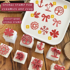 May include: A selection of red sponge stamps for ceramics and clay, including an anchor, palm trees, a tree, a maple leaf, bows, a flower, a snowflake, and a four-leaf clover. The text reads "SPONGE STAMP FOR CERAMICS AND CLAY" and "SELECT YOUR SPONGE STAMP."