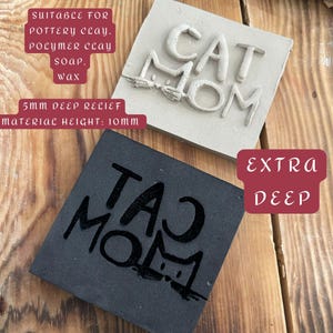 May include: Two square stamps, one light gray and one black, with the words "CAT MOM" and "TAO MOM" embossed. The light gray stamp has a 5mm deep relief and a material height of 10mm. The stamps are suitable for pottery clay, polymer clay, soap, and wax.