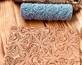 May include: A blue patterned roller and a brown rectangular piece with an octopus design. The roller is cylindrical and features a repeating octopus tentacle pattern. The rectangular piece has a similar embossed design. The items are on a wooden surface.