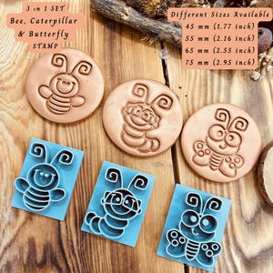 May include: A set of three stamps featuring bee, caterpillar, and butterfly designs. The stamps are round and made of a light brown material. The set includes blue plastic cutters in the same designs. Sizes available: 45 mm (1.77 inch), 55 mm (2.16 inch), 65 mm (2.55 inch), and 75 mm (2.95 inch).