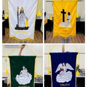 May include: Four decorative banners in white, yellow, green, and blue. Each banner features a different illustration and the words "Wisdom", "Faith", "Charity", and "Truth". The banners are trimmed with gold fringe and tassels.