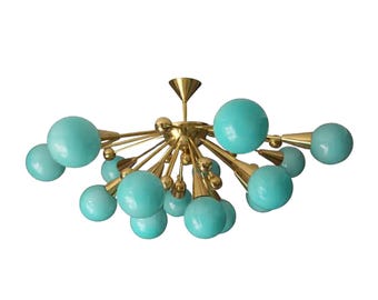 May include: A mid-century modern chandelier with a brass finish and turquoise globe-shaped lights. The fixture has multiple arms extending from a central point, each ending in a turquoise sphere. The design is reminiscent of atomic age aesthetics.