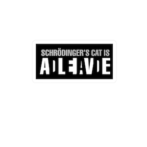 May include: A white sticker with a black rectangle containing the text "SCHRÖDINGER'S CAT IS ALIVE" in white and gray lettering. The sticker is rectangular with rounded corners and is set against a white background.