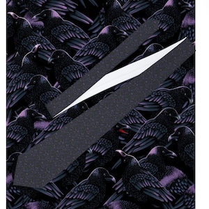 Peut inclure: Une cravate gris foncé avec un motif de corbeaux noirs et des accents violets. La cravate est posée en diagonale sur un fond du même motif de corbeaux. La cravate a une doublure blanche.